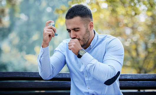 Man using asthma inhaler. Health care concept